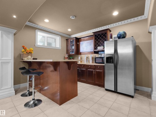Kitchenette featuring a built-in bar, stainless steel refrigerator, dark wood-finish cabinetry, recessed lighting, and tiled flooring - 1511 69 Street, Edmonton, AB - Indoor Photo Showing Kitchen
