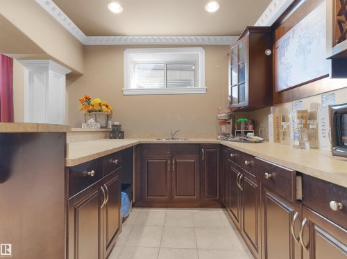 U-shaped kitchen area featuring dark wood-finish cabinetry, light-toned countertops, and a tiled floor - 1511 69 Street, Edmonton, AB - Indoor Photo Showing Kitchen