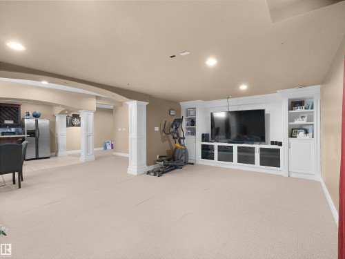 Spacious entertainment area featuring a built-in media center with shelving, recessed lighting, carpeted flooring, and architectural columns - 1511 69 Street, Edmonton, AB - Indoor