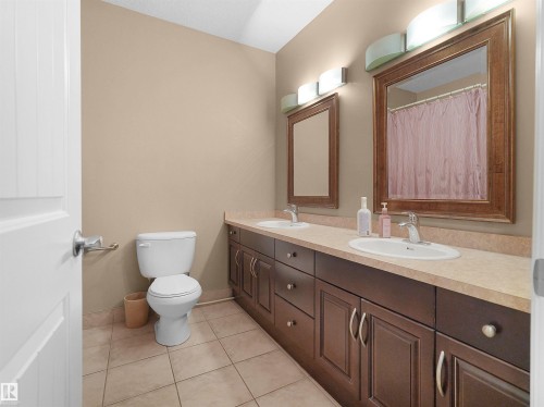 Dual vanity with warm wood-finish cabinetry, integrated sinks, and individual framed mirrors - 1511 69 Street, Edmonton, AB - Indoor Photo Showing Bathroom