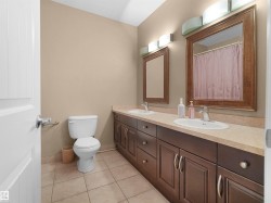 Dual vanity with warm wood-finish cabinetry, integrated sinks, and individual framed mirrors - 