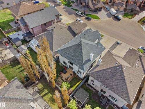 Fenced backyard featuring a multi-level wood deck, a patio area, mature trees, and an adjacent greenhouse structure - 1511 69 Street, Edmonton, AB - Outdoor With View