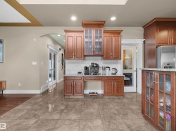 Kitchenette area featuring wood-finish cabinetry, granite countertops, and a tiled backsplash - 