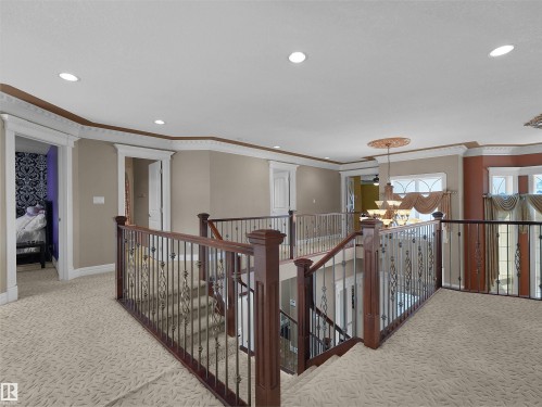 Upper landing featuring an elaborate chandelier, recessed lighting, patterned carpeting, and decorative wrought iron and wood stair railings - 1511 69 Street, Edmonton, AB - Indoor Photo Showing Other Room