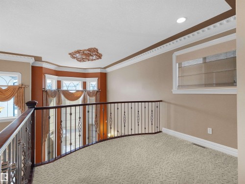 Upper-level landing featuring decorative wrought iron railing, patterned carpet flooring, recessed lighting, and crown molding - 1511 69 Street, Edmonton, AB - Indoor Photo Showing Other Room