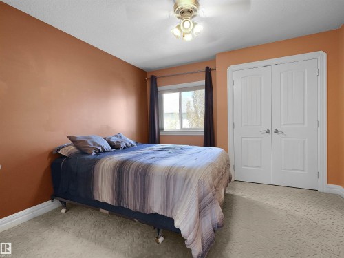 Bedroom featuring light-toned patterned carpeting, a double-door closet with paneling, a ceiling fan with integrated lighting, and a single window with dark drapery - 1511 69 Street, Edmonton, AB - Indoor Photo Showing Bedroom