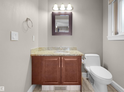 Bathroom featuring a vanity with granite-style countertop, wood-finish cabinetry, and an integrated sink basin - 1511 69 Street, Edmonton, AB - Indoor Photo Showing Bathroom