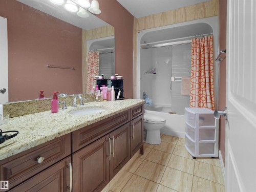 Bathroom featuring a spacious granite-look countertop, dark wood-finish vanity with multiple storage cabinets, and a large wall-mounted mirror - 1511 69 Street, Edmonton, AB - Indoor Photo Showing Bathroom