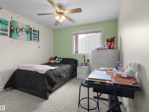 Bedroom featuring a ceiling fan with integrated lighting, a window with blinds, light-toned walls with a contrasting accent wall, and patterned carpeting - 1511 69 Street, Edmonton, AB - Indoor Photo Showing Bedroom
