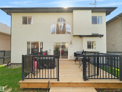 Rear exterior featuring a spacious wood deck with black metal railings, a stucco finish facade, and a large arched window - 1511 69 Street, Edmonton, AB - Outdoor With Exterior