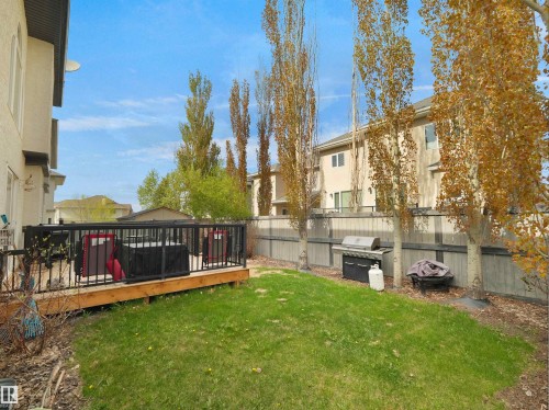 Expansive backyard featuring a wood deck with black railings, a manicured lawn, and mature trees providing natural screening - 1511 69 Street, Edmonton, AB - Outdoor With Deck Patio Veranda