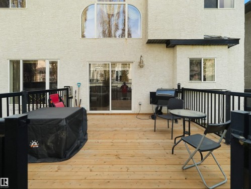 Spacious wood deck with black metal railings, white stucco exterior, sliding glass door access, and an arched window feature - 1511 69 Street, Edmonton, AB - Outdoor With Deck Patio Veranda With Exterior
