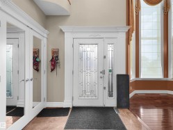 Grand entryway featuring a decorative glass front door with sidelights, complemented by ornate white trim - 