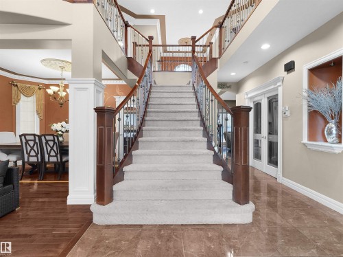 Grand staircase featuring carpeted treads, wood handrails, and wrought iron balusters - 1511 69 Street, Edmonton, AB - Indoor Photo Showing Other Room