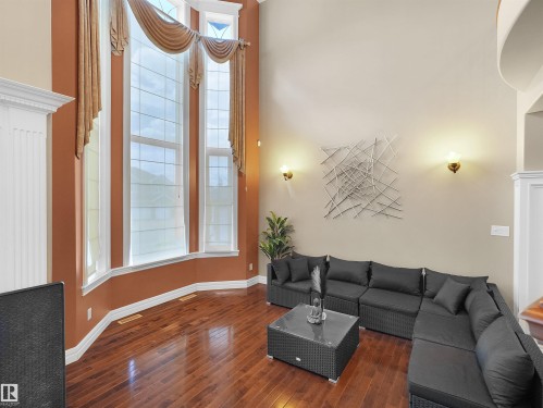 Two-story window wall featuring decorative valances, wood-finish flooring, and sconce lighting - 1511 69 Street, Edmonton, AB - Indoor Photo Showing Living Room