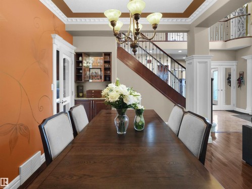 Formal dining area featuring a dark wood-finish table with upholstered chairs, an accent wall with a subtle botanical motif, and decorative crown molding - 1511 69 Street, Edmonton, AB - Indoor Photo Showing Dining Room