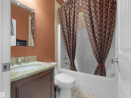 Bathroom featuring a built-in vanity with a light-colored stone countertop, undermount sink, and dark wood-finish cabinetry - 1511 69 Street, Edmonton, AB - Indoor Photo Showing Bathroom