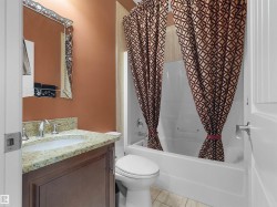 Bathroom featuring a built-in vanity with a light-colored stone countertop, undermount sink, and dark wood-finish cabinetry - 