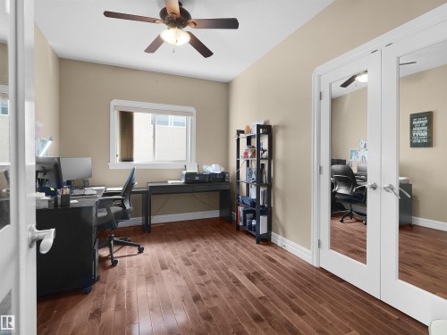 Versatile room featuring rich wood-finish flooring, a ceiling fan, and a wide window with white trim - 1511 69 Street, Edmonton, AB - Indoor Photo Showing Office