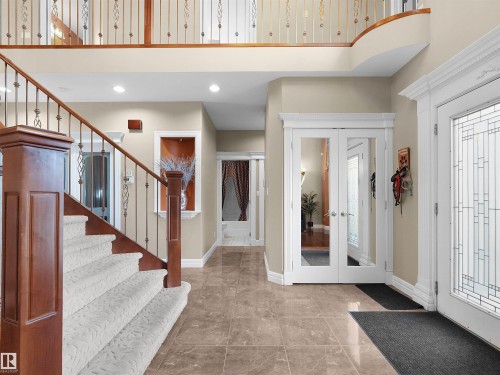 Grand foyer featuring large format tile flooring and a curved staircase with carpeted treads, wood newel posts, and wrought iron balusters - 1511 69 Street, Edmonton, AB - Indoor Photo Showing Other Room