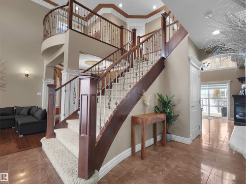 Grand foyer featuring a curved staircase with dark wood newel posts and wrought iron balusters - 1511 69 Street, Edmonton, AB - Indoor Photo Showing Other Room