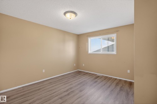 Interior room featuring wood-finish flooring, light tan wall paint, and a textured white ceiling - 5204 55 Ave, Mundare, AB - Indoor Photo Showing Other Room