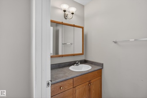 Bathroom vanity featuring a wood-finish cabinet, a built-in sink, and a dark countertop - 5204 55 Ave, Mundare, AB - Indoor Photo Showing Bathroom