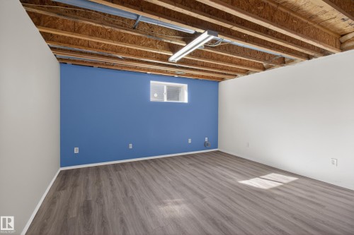 Spacious room featuring wood-finish flooring, a painted accent wall, and a window for natural light - 5204 55 Ave, Mundare, AB - Indoor