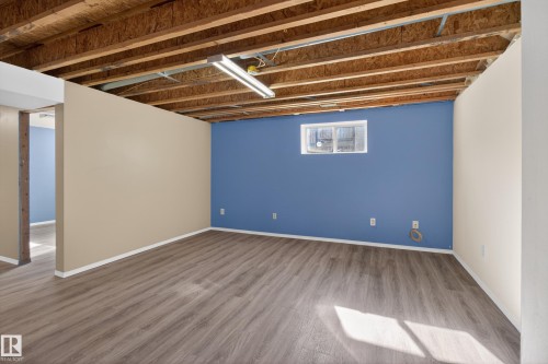 Lower level space featuring wood-finish flooring, exposed ceiling joists, and a window for natural light - 5204 55 Ave, Mundare, AB - Indoor Photo Showing Other Room