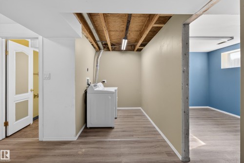 Laundry area featuring wood-finish flooring, exposed ceiling joists, and beige walls - 5204 55 Ave, Mundare, AB - Indoor