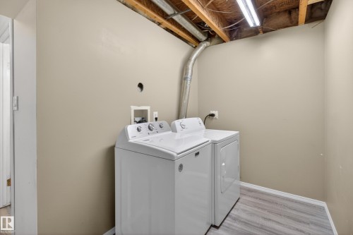 Dedicated laundry area featuring wood-finish flooring, neutral-toned walls, and exposed ceiling joists - 5204 55 Ave, Mundare, AB - Indoor Photo Showing Laundry Room