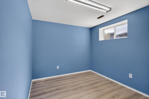 Room featuring wood-finish flooring, a white ceiling with a fluorescent light fixture, and a single window - 5204 55 Ave, Mundare, AB - Indoor Photo Showing Other Room