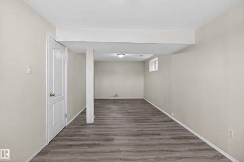 Versatile room featuring wood-finish flooring, light neutral wall tones, a paneled door with brass hardware, and recessed lighting - 5204 55 Ave, Mundare, AB - Indoor Photo Showing Other Room