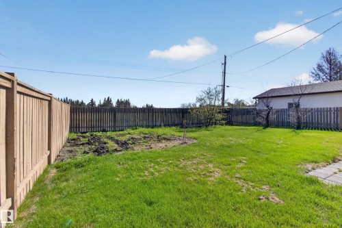 Expansive grassy yard area featuring a combination of wood privacy fencing and picket fencing - 5204 55 Ave, Mundare, AB - Outdoor