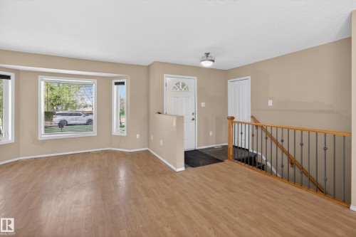 Open-concept living space featuring wood-finish flooring, a bay window with blinds, and neutral wall paint - 5204 55 Ave, Mundare, AB - Indoor Photo Showing Other Room
