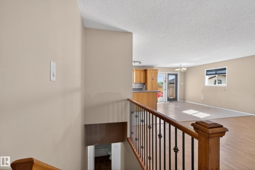 Open-concept living area featuring wood-finish flooring, a kitchen with wood cabinetry and a breakfast bar, and a dining space with an attached chandelier - 5204 55 Ave, Mundare, AB - Indoor Photo Showing Other Room