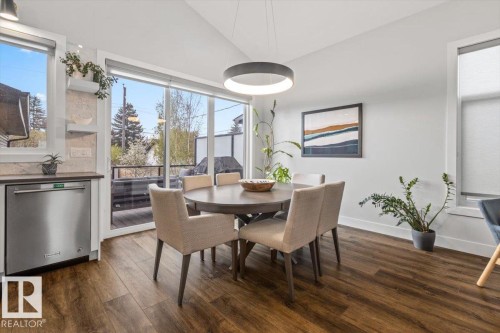 Dining area featuring wood-finish flooring, a modern circular chandelier, and a stainless steel dishwasher - 10611 146 Street Nw, Edmonton, AB - Indoor Photo Showing Dining Room