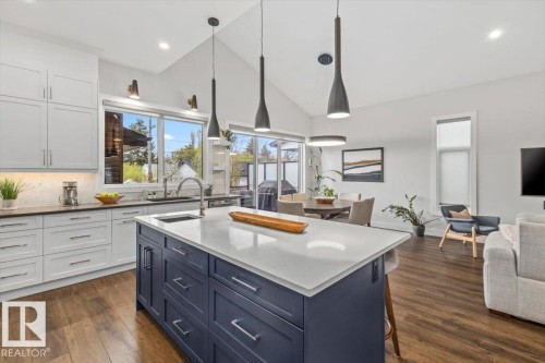 Open-concept kitchen featuring a navy blue island with a light-toned countertop, wood-finish flooring, and white upper and lower cabinetry - 10611 146 Street Nw, Edmonton, AB - Indoor Photo Showing Kitchen With Upgraded Kitchen