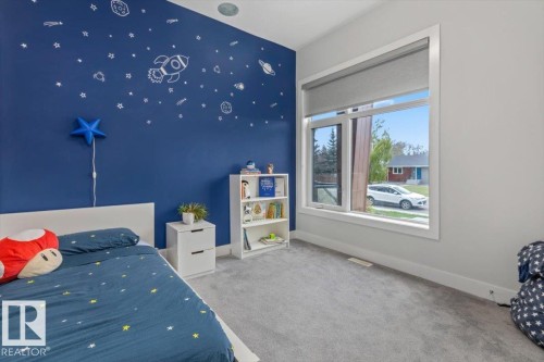 Light gray carpeted room featuring a large window with white trim, a blue accent wall, and a built-in ceiling light fixture - 10611 146 Street Nw, Edmonton, AB - Indoor
