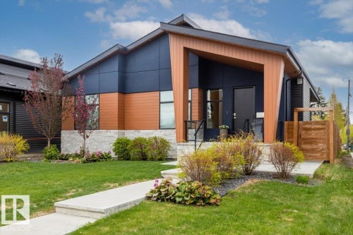 Modern architectural home featuring a multi-tone facade with dark paneling, wood-finish siding, and stone accents - 10611 146 Street Nw, Edmonton, AB - Outdoor