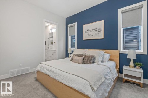 Bedroom featuring a contrasting accent wall, two windows with roller shades, and plush carpeting - 10611 146 Street Nw, Edmonton, AB - Indoor Photo Showing Bedroom