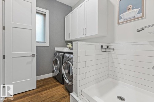 Dedicated laundry area featuring wood-finish flooring and a built-in utility shower with white subway tile - 10611 146 Street Nw, Edmonton, AB - Indoor Photo Showing Laundry Room