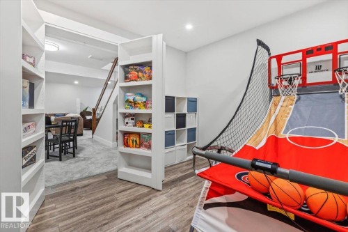 Open concept recreation area featuring wood-finish flooring, built-in shelving, recessed lighting, and a white color palette - 10611 146 Street Nw, Edmonton, AB - Indoor Photo Showing Other Room