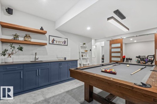 Recreation room featuring a modern linear light fixture and a sliding barn door with frosted glass panels - 10611 146 Street Nw, Edmonton, AB - Indoor Photo Showing Other Room