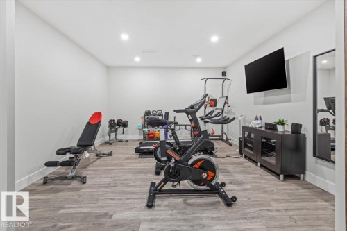 Dedicated exercise room featuring wood-finish flooring, recessed lighting, and a wall-mounted display - 10611 146 Street Nw, Edmonton, AB - Indoor Photo Showing Gym Room