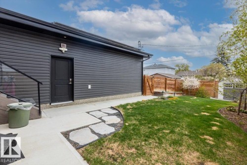 Exterior featuring dark siding, a private entry, a concrete walkway, a stone path, and a manicured lawn - 10611 146 Street Nw, Edmonton, AB - Outdoor