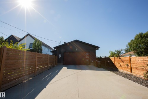 Detached garage with a paneled door and dark siding, fronted by a concrete driveway - 10611 146 Street Nw, Edmonton, AB - Outdoor With Exterior