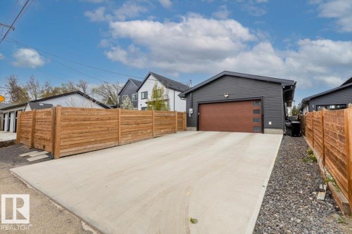 Contemporary detached garage featuring dark siding and a wood-finish garage door with frosted window panels - 10611 146 Street Nw, Edmonton, AB - Outdoor