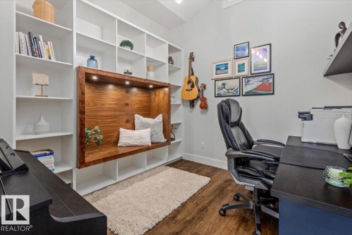 Built-in shelving unit with a recessed wood-finish bench featuring integrated lighting, complemented by wood-finish flooring - 10611 146 Street Nw, Edmonton, AB - Indoor Photo Showing Office