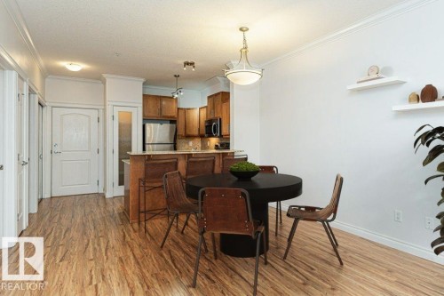 Open-concept kitchen and dining area featuring wood-finish flooring, recessed lighting, and crown molding - 145 10121 80 Avenue, Edmonton, AB - Indoor